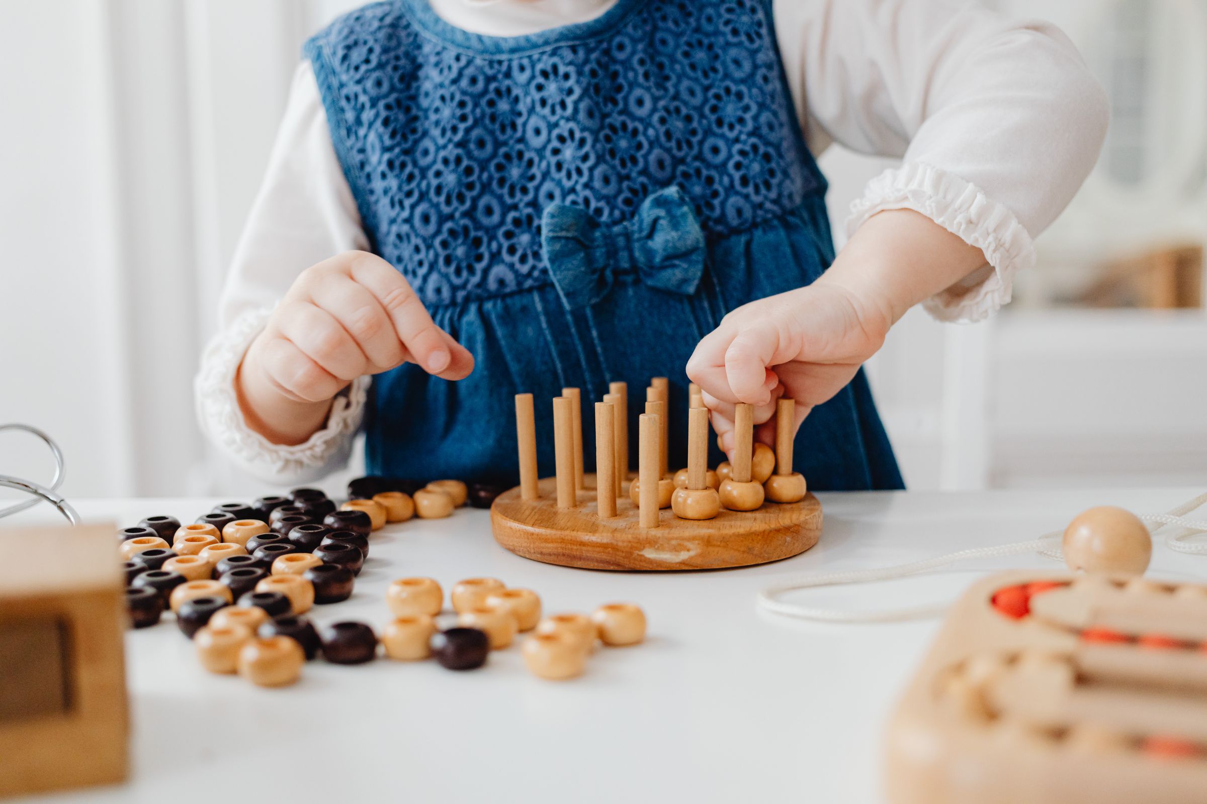 A child's hands working with genuine Montessori bead and peg material